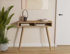 a wooden table sitting next to a potted plant on top of a hard wood floor