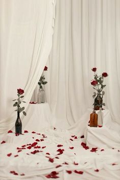 two vases filled with roses sitting next to each other on a white cloth covered floor