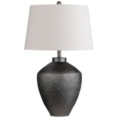 a lamp that is on top of a white table cloth next to a black vase