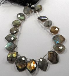 a necklace made out of labradorite beads and black feathers on a white table top