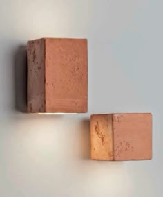 two brick lights mounted on the side of a wall, one is orange and the other is brown