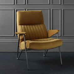 a yellow chair sitting on top of a black floor next to a wall with grey paneling