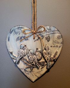 a wooden heart hanging from a rope with birds on it