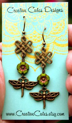 Rustic bronze dragonflies sway from earthy green glass flowers & bronze Celtic knots...Outlander Inspired! Uniquely hand crafted with these quality materials: ~ Czech glass flower beads with a gold Picasso finish ~ Antiqued Brass dragonfly and Celtic knot charms ~ Antiqued brass lead & nickel-free French hook style ear wires ~ Silicone earring backs to keep earrings securely in ears Measuring 2~1/4 inches from the top of the ear wires to the bottom of the charms, they're comfortably ligh Handmade Bohemian Green Flower Earrings, Handmade Green Bohemian Flower Earrings, Green Bohemian Flower Earrings For Gift, Nature-inspired Green Dangle Flower Earrings, Artistic Green Flower-shaped Jewelry, Bohemian Wire Wrapped Flower Earrings, Bohemian Bronze Flower Earrings Nickel-free, Bohemian Bronze Flower Earrings Nickel Free, Green Adjustable Dangle Flower Earrings