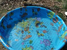 a large blue plastic bowl with fish and sea animals on it sitting in the grass