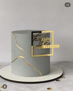 a white and gold birthday cake sitting on top of a plate