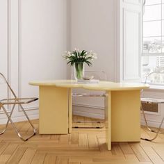 a yellow table and two chairs in a room with white walls, hardwood floors and windows