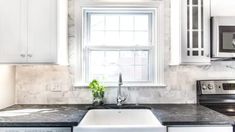 a kitchen with marble counter tops and white cabinets, along with a window above the sink