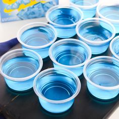 there are many blue bowls on the table with plastic cups in front of each other