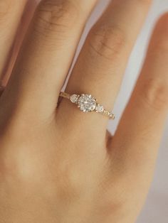 a woman's hand with a diamond ring on top of her finger and the bottom half of her wedding band