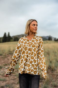 THIS SALE ITEM IS FINAL SALE! Experience effortless style with our Rowen Top-Golden Floral! This relaxed fit top features a button down design, collared neckline, and button cuffs for added versatility. The stunning floral pattern adds a touch of femininity to any outfit. Elevate your wardrobe with this must-have piece.(One model has collar tucked in) *Relaxed fit* Material Content: 100% Polyester Material Pattern: Floral Reagan is 5’5” wearing a small Model Measurements: Reagan Height: 5'5" // Fall V-neck Blouse With Placket, Spring Split Neck Blouse With Placket, Relaxed Fit Floral Print Button-up Blouse, Chic Relaxed Fit Blouse With Floral Print, Chic Blouse With Floral Print And Relaxed Fit, Flowy Floral Print Blouse For Work, Fall Blouse With Shirttail Hem And Placket, Workwear Flowy Floral Print Blouse, Printed Relaxed Fit Button-up Blouse