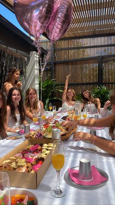 a group of women sitting around a table with food and drinks