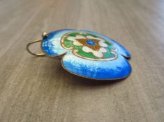 "These vintage 1970s cloisonné enamel pierced earrings feature a large flower, or Kamon Japanese Family Crest, in sterling silver 24k gold wash. The enamel colors are Sapphire, Light Sapphire, Chalk White, Emerald and Light Smoked Topaz. The earrings measure approximately 1-1/2\" in length, 1-1/4\" in width, with a 1-1/4\" drop, and are marked SILVER. They were handmade by Chinese artisans. This pair is similar to those from Laurel Burch's 1970s \"Stone Collection,\" and similar to Laurel Burch, Vintage Pierced Enamel Jewelry, Antique Enamel Earrings As Gift, Antique Enamel Earrings For Gift, Handmade Gold Enamel Pin, Vintage Enamel Wedding Earrings, Collectible Enamel Jewelry With Matching Earrings, Vintage Enamel Jewelry With Matching Earrings, Vintage Hand Painted Enamel Earrings, Vintage Hand-painted Enamel Earrings