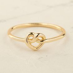 Our 14K Gold Twisted Heart Knot Ring is the epitome of elegance and heartfelt symbolism. This exquisite piece is carefully handcrafted from real 14K solid gold, ensuring both quality and luxury. The ring features a unique heart knot design, created from twisted gold wire, measuring 6.25 mm by 6.90 mm. This delicate yet striking design makes the ring a versatile piece, suitable for everyday wear or special occasions. Available in your choice of gold, rose gold, or white gold, this ring caters to Gold Open Heart Ring Gift, Adjustable Yellow Gold Rings For Valentine's Day, Elegant Sterling Silver Heart Ring In Yellow Gold, Adjustable Double Heart Gold Ring, Symbolic Wedding Rings For Valentine's Day, Adjustable Yellow Gold Heart-shaped Rings, Adjustable Heart-shaped Yellow Gold Rings, Double Heart Yellow Gold Promise Jewelry, Gold Open Heart Jewelry For Promise