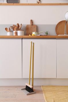 two brooms in the middle of a kitchen with utensils on the counter