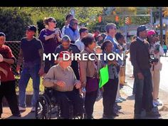 a group of people standing around each other in front of a fence with the words my direction written on it