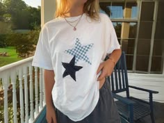 a woman standing on a porch wearing a t - shirt with a star