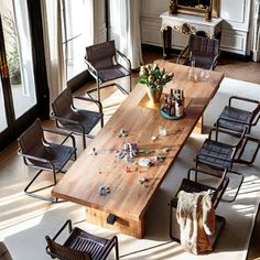 a large wooden table surrounded by chairs in a room with lots of windows and doors