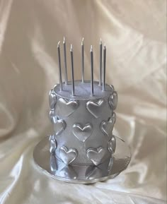 a silver cake with hearts and candles on it