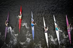 several people in canoes paddling through the water on their backs and arms up