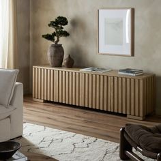 a living room with a couch, chair and potted plant on the sideboard