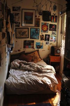 an unmade bed with lots of pictures on the wall