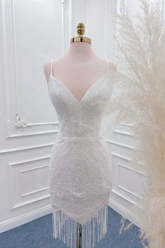 a white dress on display in front of a mannequin with feathers around it