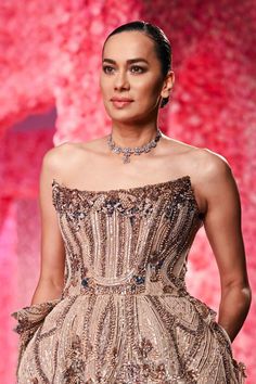 a woman in a dress on the catwalk at a fashion show wearing an elaborate necklace