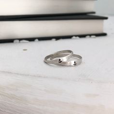 two silver rings sitting next to each other on top of a table near a stack of books