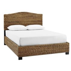 a wicker bed with white sheets and pillows on it's headboard is shown