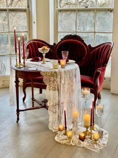 a table with candles on it in front of two chairs and a couch next to each other