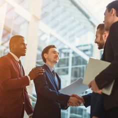 three men in suits shaking hands with each other