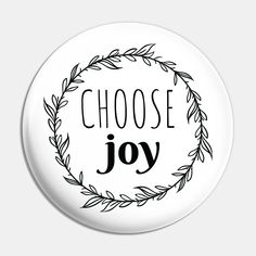 a white button with the words choose joy in black ink on it, surrounded by leaves