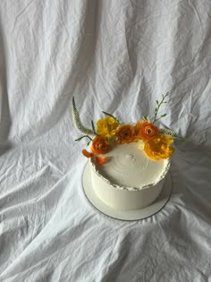 a white cake topped with flowers on top of a white tablecloth covered table cloth