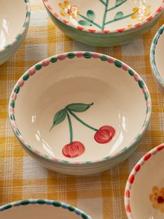 many bowls with flowers painted on them sitting on a tablecloth covered table in front of each other