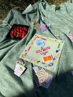 a monopoly board game on a blanket with strawberries