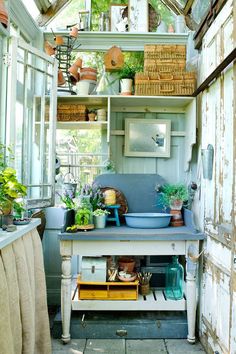 an outdoor kitchen with lots of potted plants on the counter and shelves above it