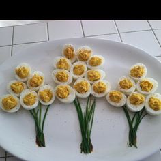 there are nine eggs arranged in the shape of flowers on a white plate with green stems