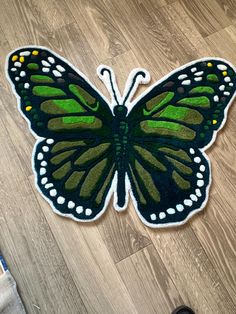 a green and black butterfly sitting on top of a wooden floor