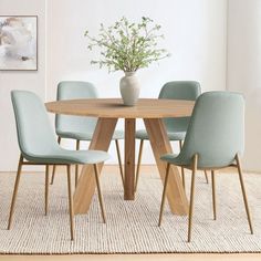 a dining table with four chairs and a vase on the top, in front of a white wall