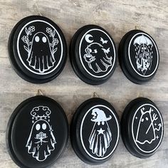 six black and white buttons with designs on them sitting on a wooden table next to each other