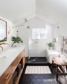 a bathroom with black and white tile flooring, wooden cabinetry, and gold accents