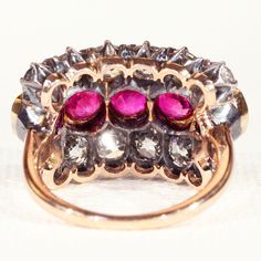 This show stopping Victorian Ring contrasts bright and sparkling Old cut diamonds with lively rich red rubies. Made in England c. 1890. The ring showcases twelve Old European cut diamonds with a total weight of 4 carats. 5 round faceted rubies with a total weight of 3.05 carats. All measurements have been done in the mount and are approximate. Eight Old European cut diamonds measure 4.5 x 2.8 mm = .4 carats each. 4 measure 3.5 x 2.4 mm = .2 carats each. Five rubies measure 5 x 3.4 mm = .61 carat Luxury Red Diamond Ring With Single Cut Diamonds, Luxury Ruby Diamond Ring With Rose Cut Diamonds, Antique Ruby Ring With Single Cut Diamonds, Red Diamond Ring With Single Cut Diamonds, Luxury Red Rings With Rose Cut Diamonds, Red Ruby Cluster Ring With Rose Cut Diamonds, Luxury Red Rose Cut Diamond Rings, Antique Ruby Rings With Single Cut Diamonds, Red Victorian Diamond Ring