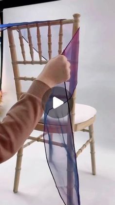 a person is holding a kite in front of a chair