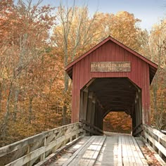 a red covered bridge surrounded by trees in the fall