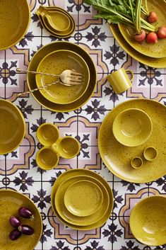 yellow dishes and utensils are arranged on a patterned tablecloth with floral designs