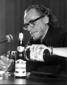 a man sitting at a table with two bottles of wine in front of him and a microphone to the side