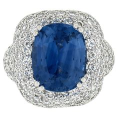 A large gorgeous BLUE and clean WELL CUT cushion sapphire sits in the middle of this magnificent ring. The cushion is saturated with a perfect blue and is well cut meaning you see all 10+ carats of this sapphire and its not wasted on the belly of the stone! It sits in a sea of white clean fiery diamonds which perform magically! This ring is not for the faint of heart and for someone who wants that sturdy heavy jewellery with a presence which is rarely seen today! GIA certified center. Enjoy! --Stone(s):-- (1) Natural Genuine Ceylon Sapphire - Cushion Cut - Prong Set - Blue Color, Slight Color Shift Depends On Light- Clean Stone - Heated - 10.28ct (exact) ** See Certification Details Below for Complete Info ** Numerous Natural Genuine Diamonds - Round Brilliant Cut - Pave Set - G/H Color - Ceylon Sapphire, Cushion Cut, Cocktail Rings, Prong Setting, Halo, Platinum, Sapphire, Blue Color, Ring Size