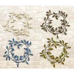 four metal wall hangings on a brick wall with leaves and vines in the center