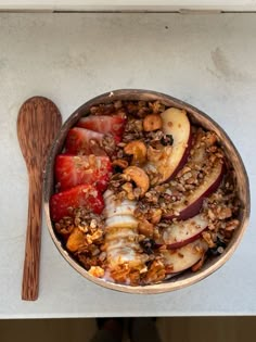 a bowl filled with granola and fruit next to a wooden spoon